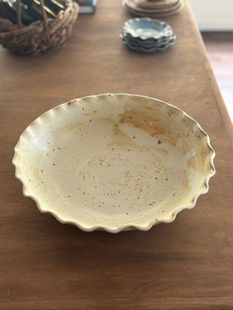 Large handmade white speckled pottery bowl with a ruffled rim, top view